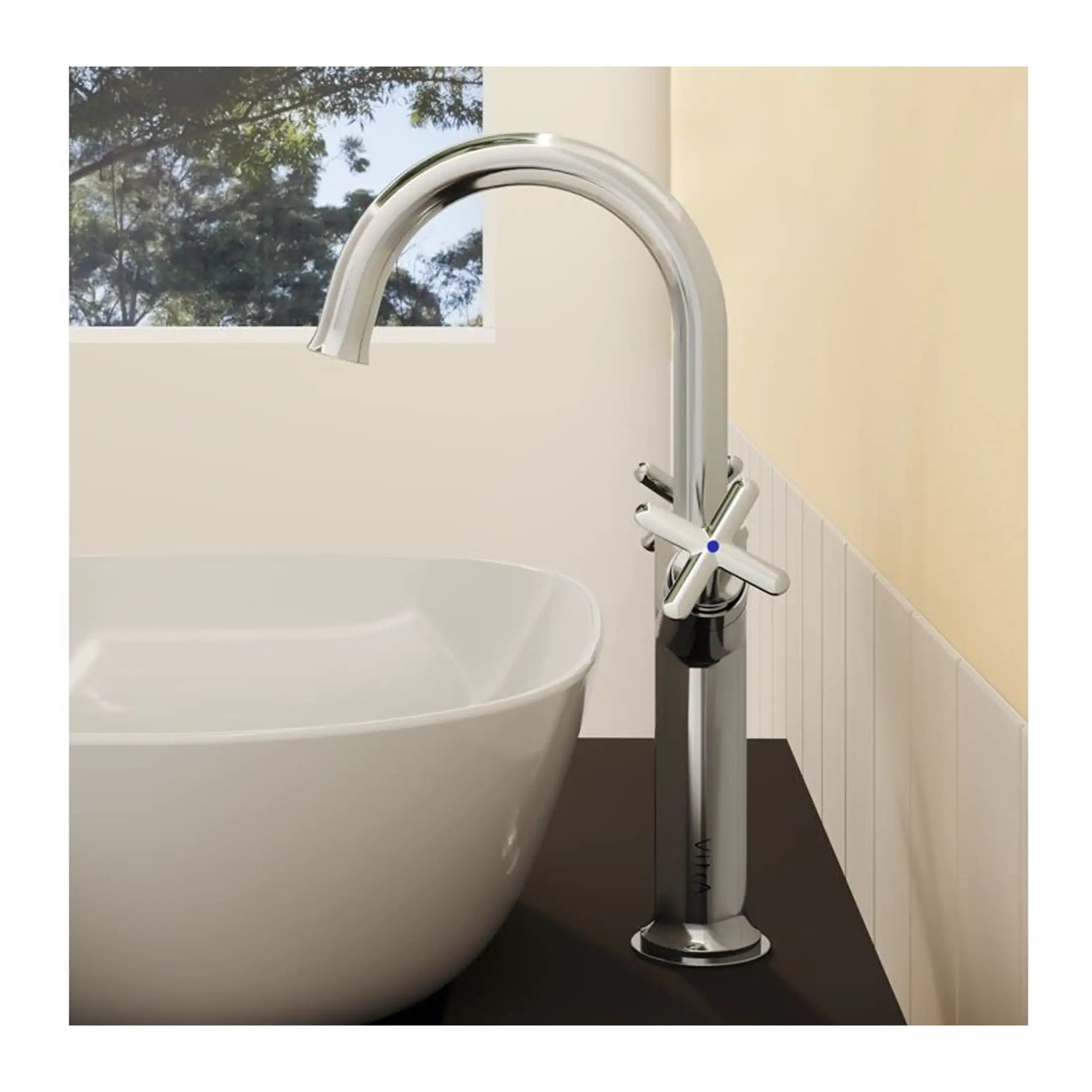 Brass bathroom mixer tap with modern cross handles next to a white bathtub, set in a contemporary bathroom with natural light and scenic window views, perfect for luxury bathroom design.
