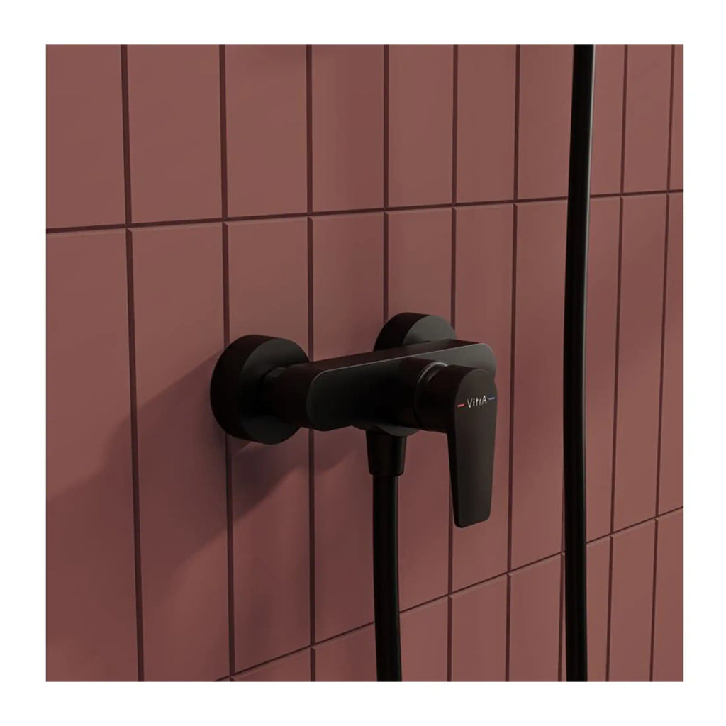 Sleek black wall-mounted shower mixer with a modern design on pink tiled bathroom wall.