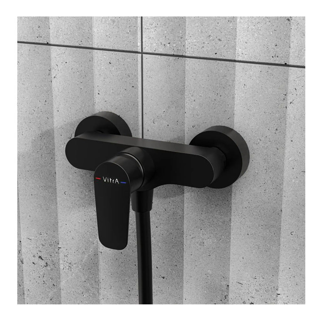 Sleek black wall-mounted bathroom mixer tap with Vitra branding, designed for modern bathrooms and shower systems, mounted on grey tiled wall.