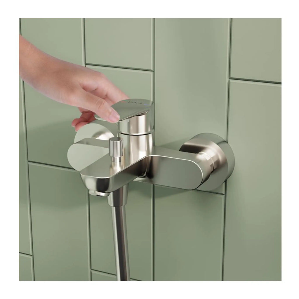 Sleek brushed stainless steel wall-mounted bathroom tap with modern lever handle, installed on a light green tiled wall, designed for contemporary bathrooms and accessible hygienic use.