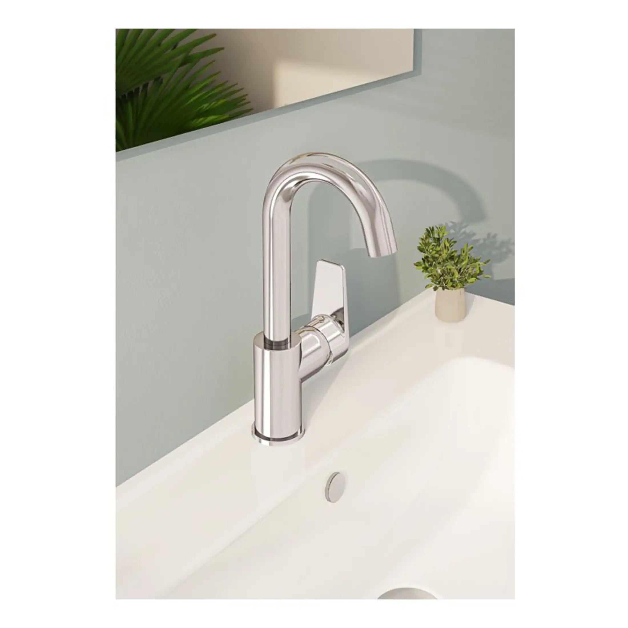 Sleek modern chrome kitchen or bathroom tap with a high arc design, installed on a white sink with a light grey wall background and a small green plant for added décor.
