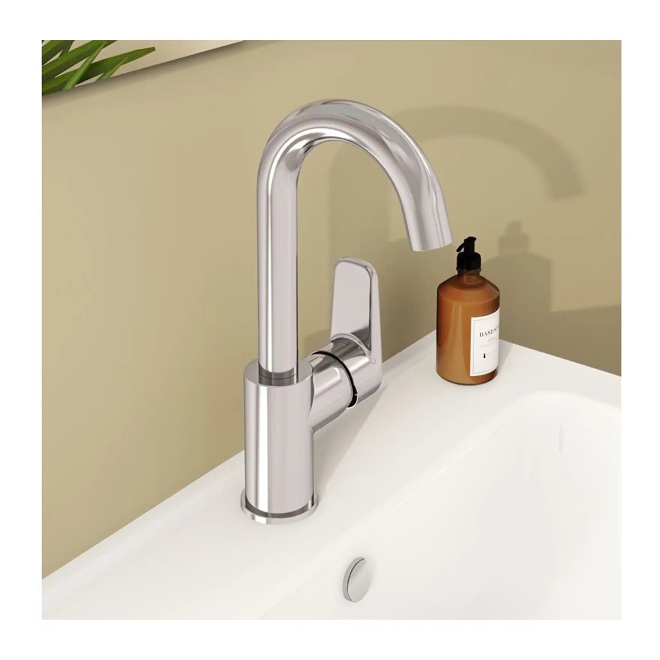 Sleek modern chrome kitchen or bathroom faucet with a curved spout installed over a white sink, accompanied by a brown hand soap dispenser on a beige wall background.