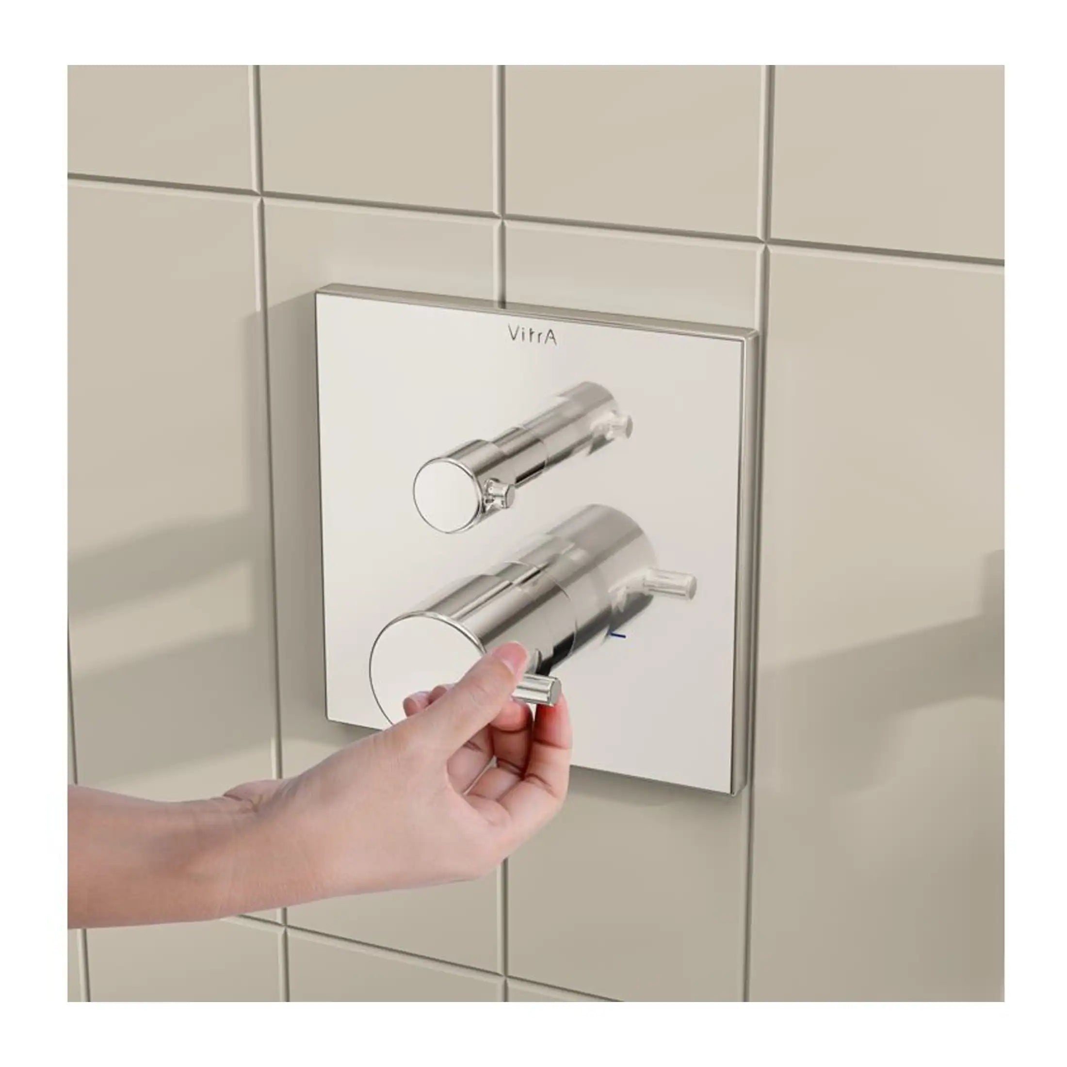 Chrome bathroom flush plate with dual flush buttons, installed on tiled wall, modern flush control for efficient water usage.