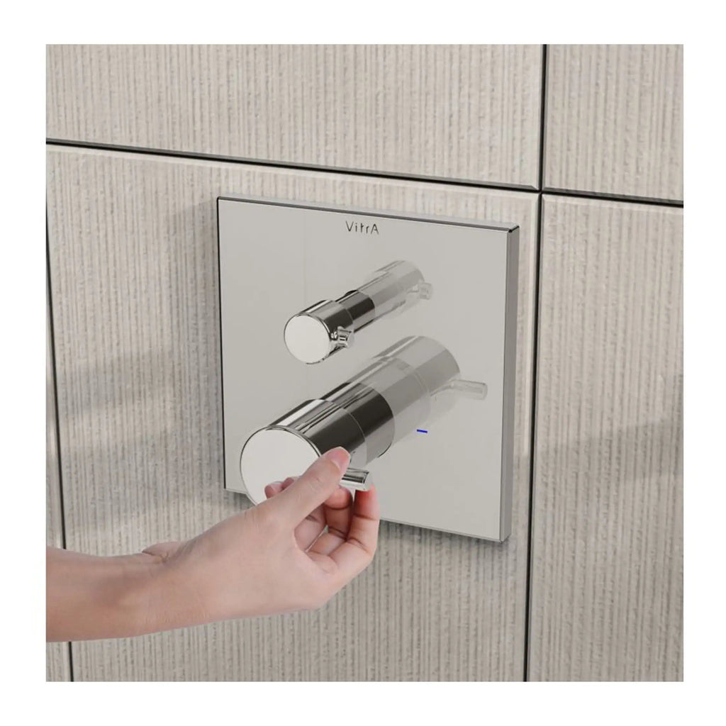 Contemporary chrome shower control panel with dual knobs, mounted on textured beige tiled wall, ideal for modern bathroom renovation.