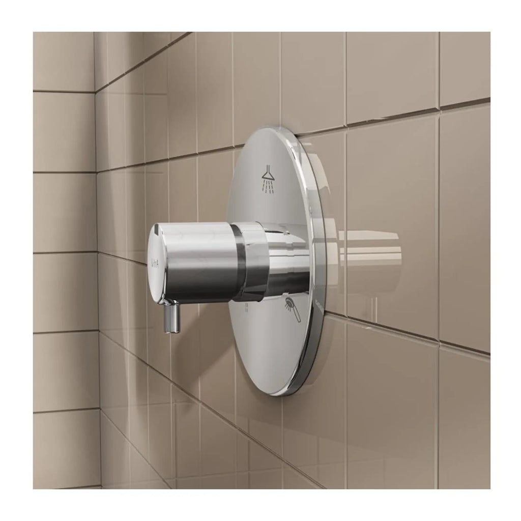 Sleek modern bathroom shower mixer with chrome finish, mounted on beige tiled wall, featuring a circular control knob and a wall-mounted showerhead icon.