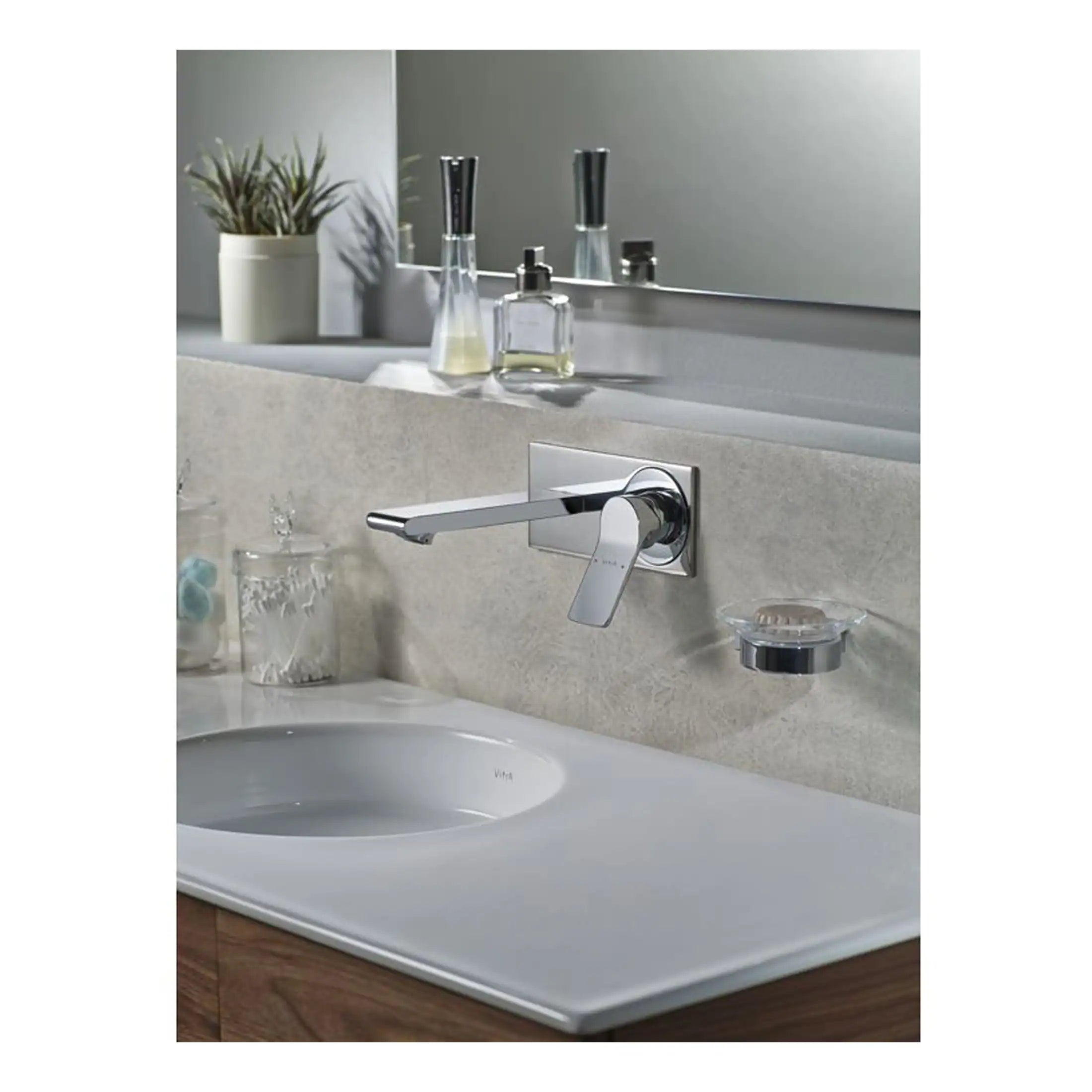 Sleek chrome bathroom tap mounted on beige stone countertop with mirror and toiletries in background.