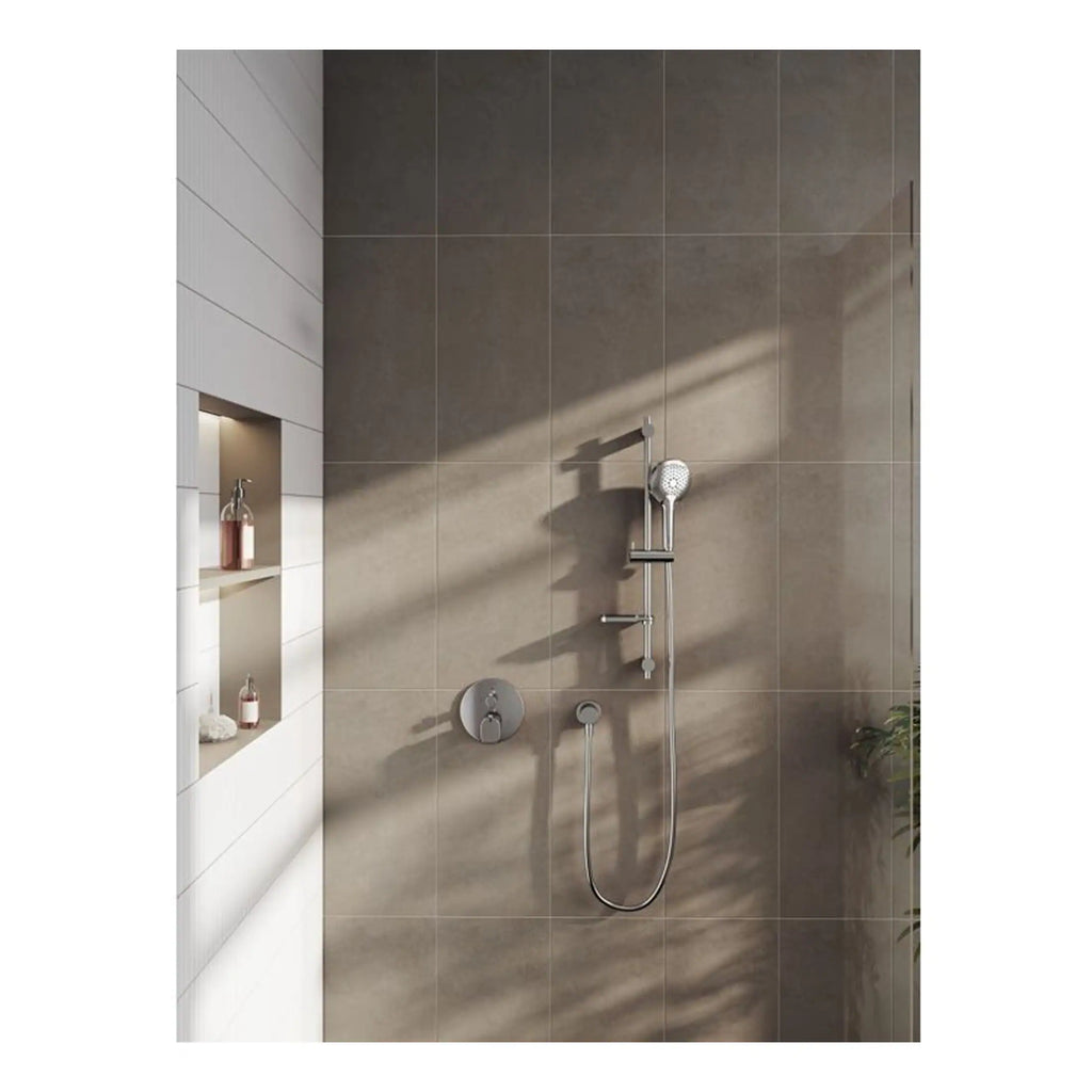 Polished silver showerhead with adjustable handheld shower and modern wall controls in a contemporary bathroom with large beige tiles.