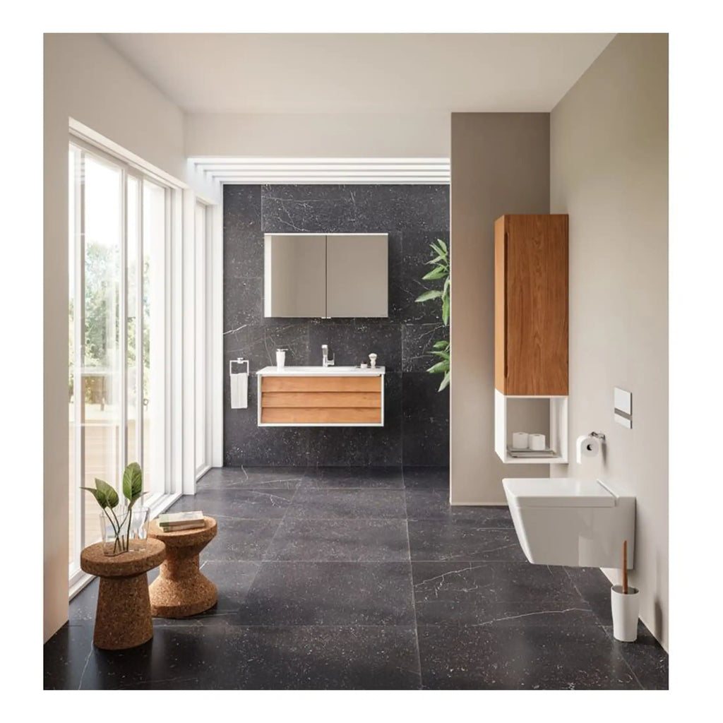 Sleek modern bathroom featuring black marble flooring and wall accents, wooden vanity with mirror, wall-mounted toilet, and natural light from large windows, showcasing contemporary and stylish design.