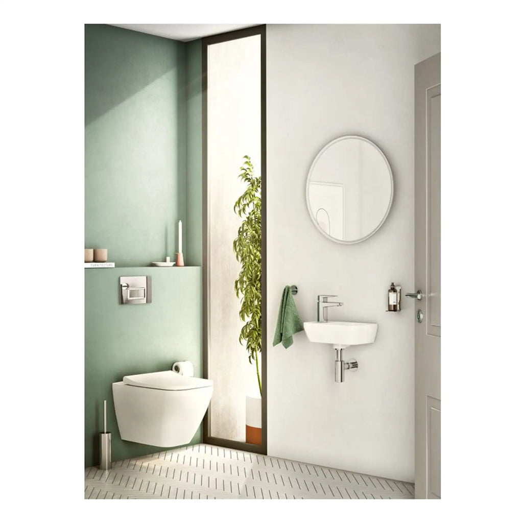 Modern minimalist bathroom featuring a wall-mounted toilet, a small wall sink, round mirror, and a walk-in shower with glass divider, designed with clean lines and neutral tones for a sleek, functional space.