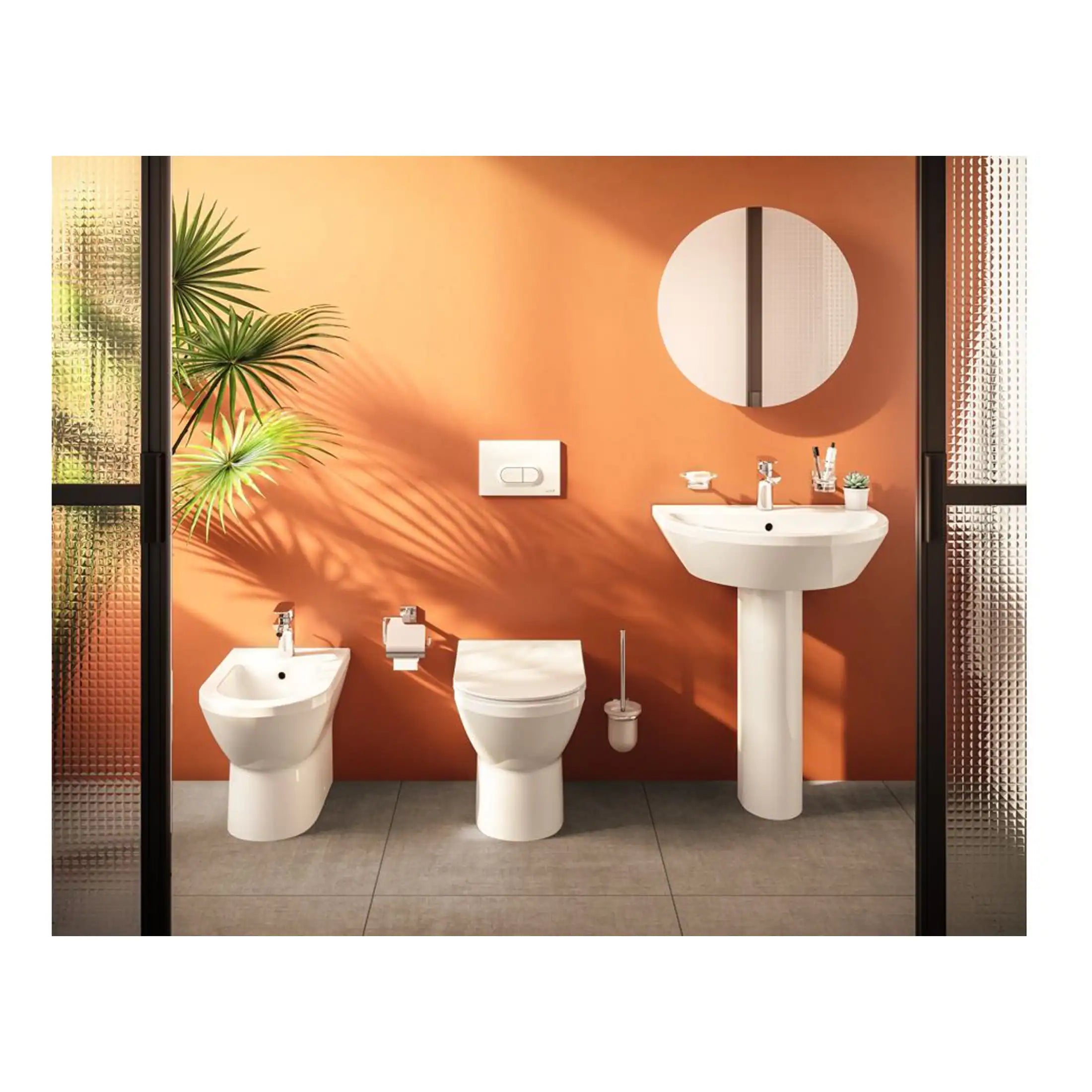 Contemporary bathroom with white toilet, bidet, and pedestal sink against an orange wall, featuring a round mirror, potted plant, and modern fixtures, showcasing stylish bathroom design.
