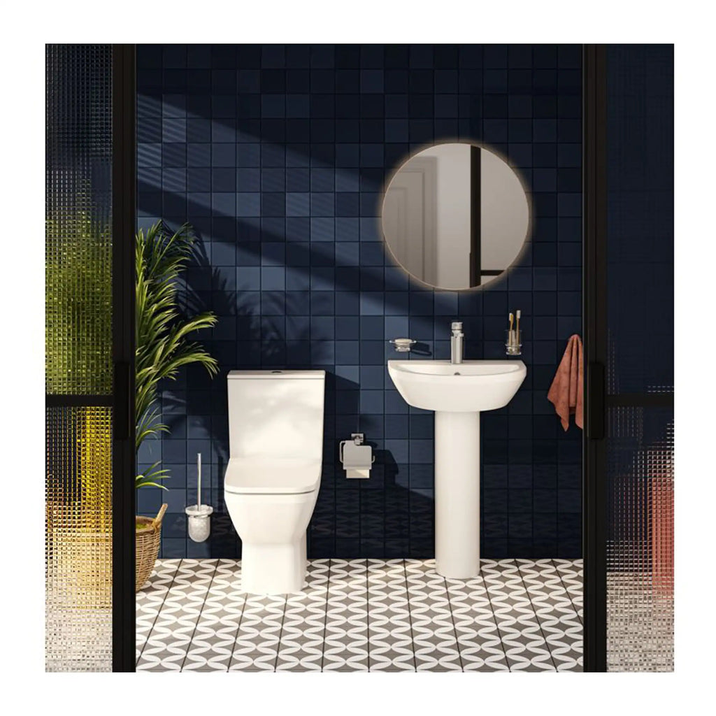 Modern bathroom featuring a sleek toilet, pedestal sink, round backlit mirror, and stylish dark tiled walls with geometric floor tiles, perfect for contemporary bathroom design.