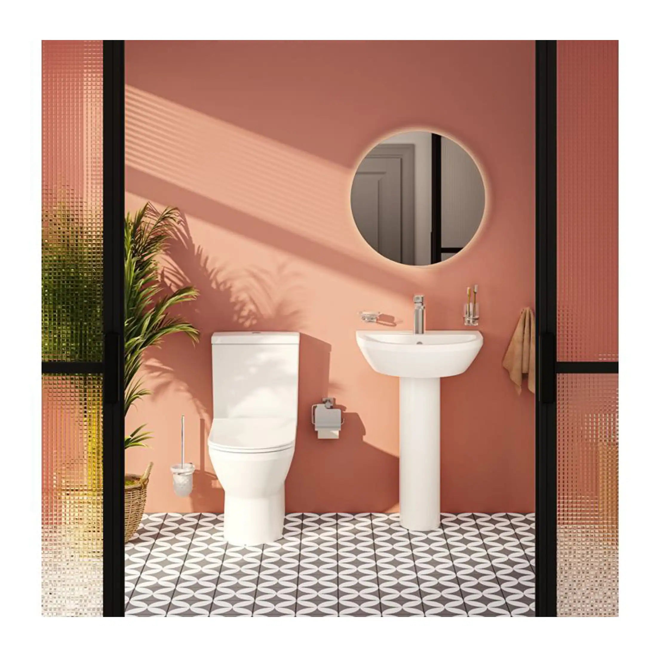 Sleek modern bathroom with pink walls, white toilet, pedestal sink, large round mirror, and black-framed glass doors, creating a stylish and functional space.