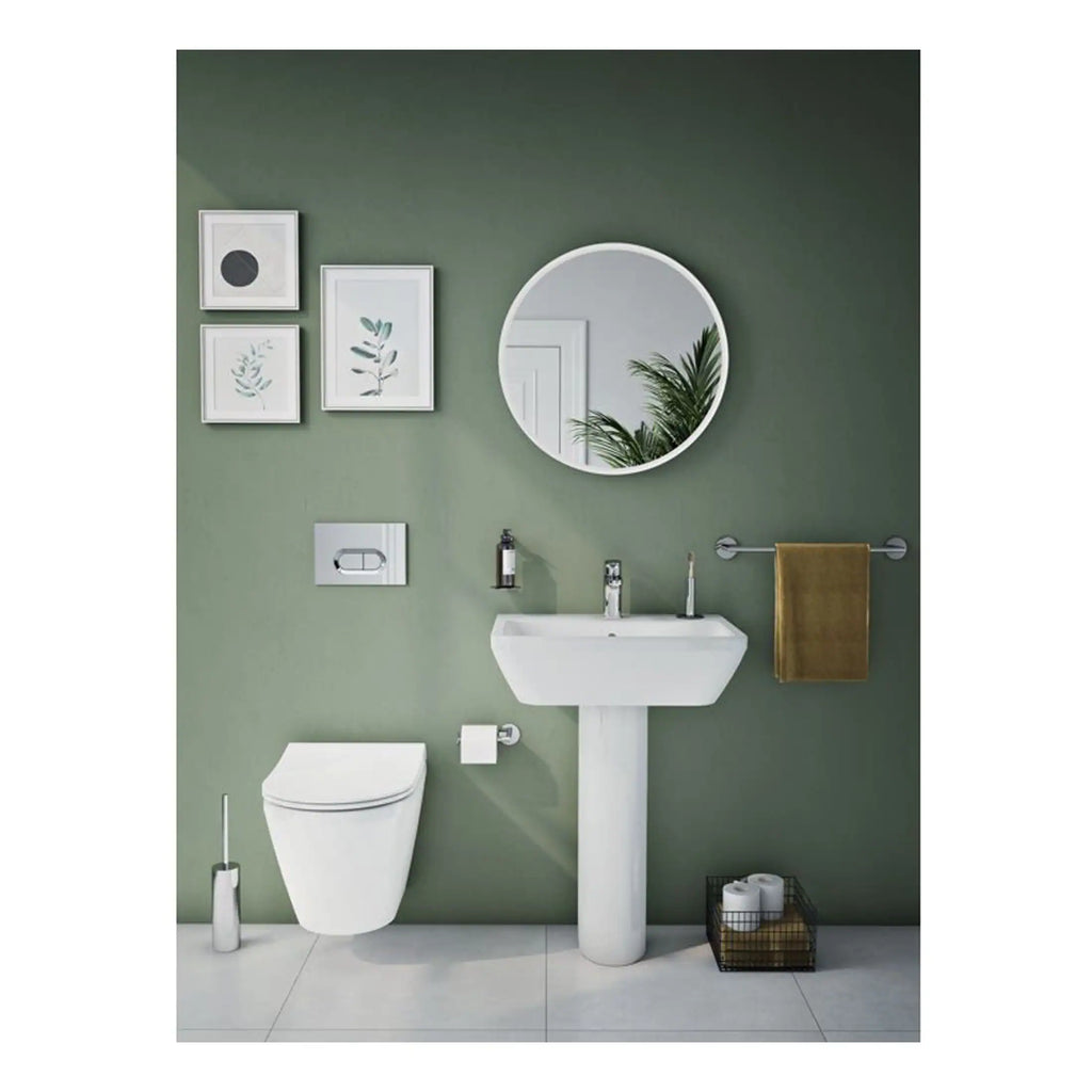 Sleek modern bathroom with green accent wall, white contemporary toilet, pedestal sink, round mirror, framed botanical art, and minimalist accessories, perfect for stylish bathroom design.