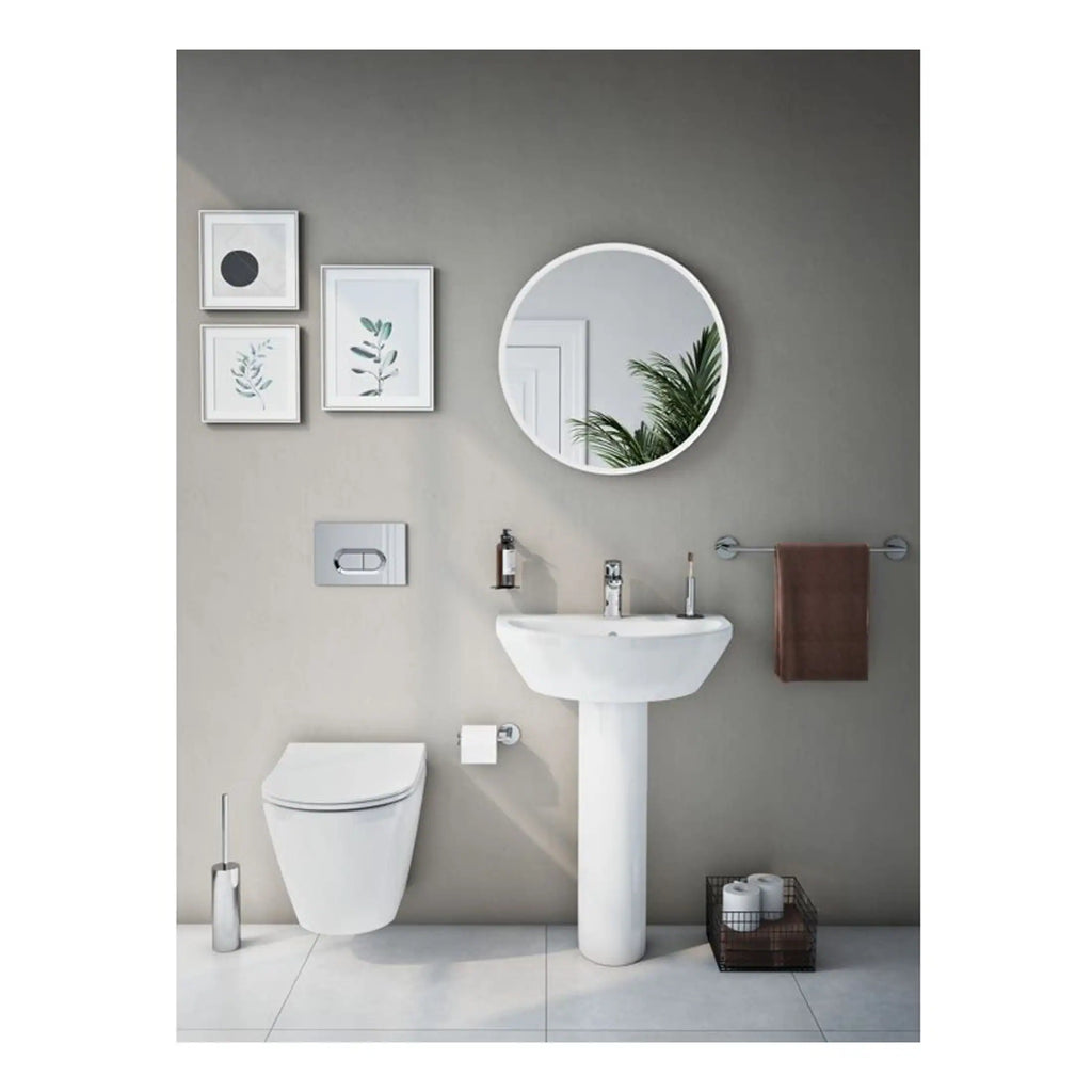 Sleek modern bathroom with wall-mounted toilet, pedestal sink, round mirror, and minimalist decor including framed botanical artwork and brown towel. Perfect for stylish bathroom renovations.