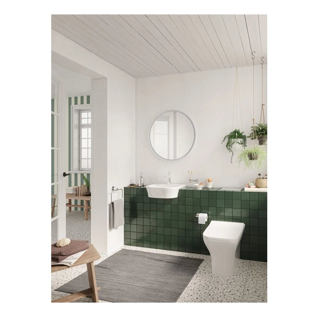 Modern bathroom with green tiled wall, white ceramic sink, and contemporary toilet, featuring hanging plants and natural light for a stylish, eco-friendly bathroom design.