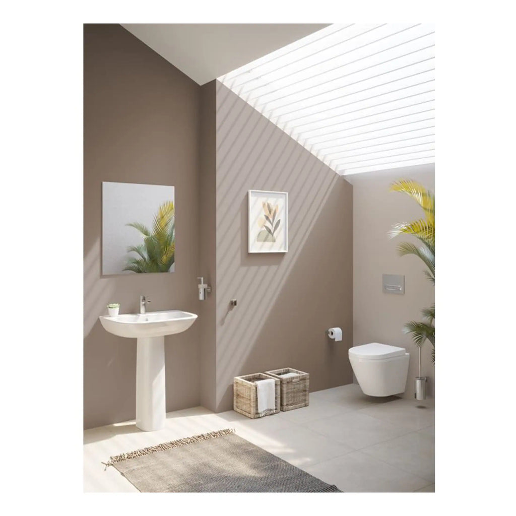 Clean modern bathroom with beige walls, pedestal sink, wall-mounted toilet, skylight, potted plants, and decorative storage baskets, showcasing stylish and functional bathroom design.