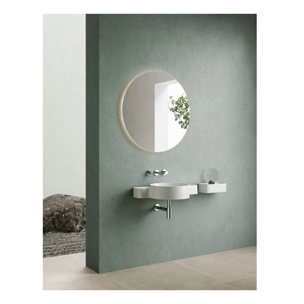 Sleek modern bathroom with a minimalist wall-mounted sink, round illuminated mirror, and soft green walls, creating a tranquil and stylish space.