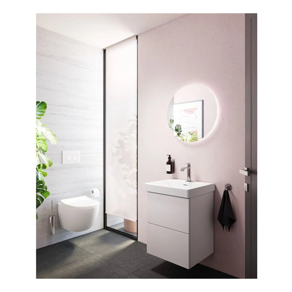 Contemporary bathroom with modern white vanity, illuminated round mirror, glass shower enclosure, and minimalistic design featuring sleek fixtures and elegant decor.