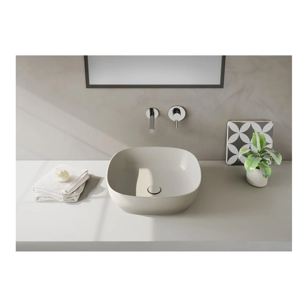 Sleek modern bathroom sink with minimalist design, featuring a wall-mounted faucet, neutral tones, and stylish decorative elements including a potted plant and patterned tiles for contemporary bathroom decor.