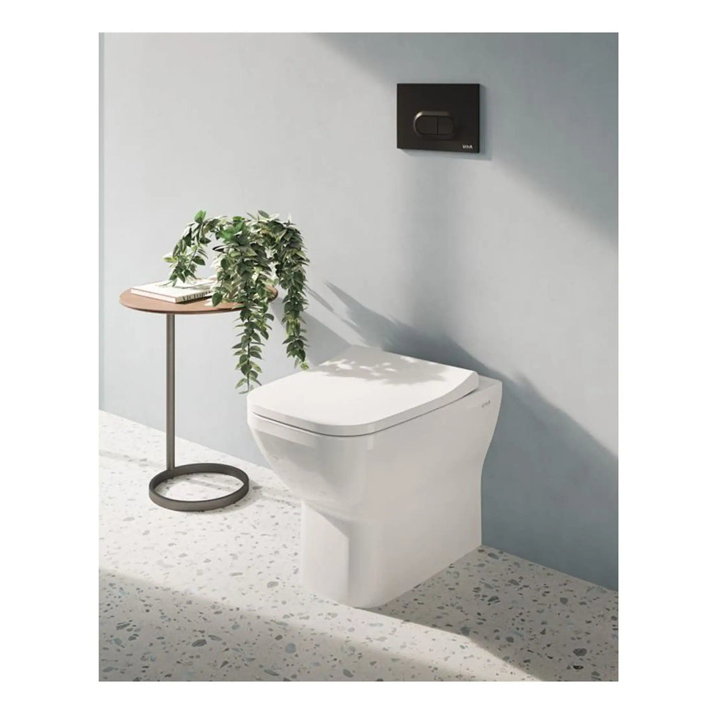 Sleek modern toilet with concealed dual flush system in bathroom with light grey wall and terrazzo flooring, showcasing minimalist water-efficient bathroom fixtures.