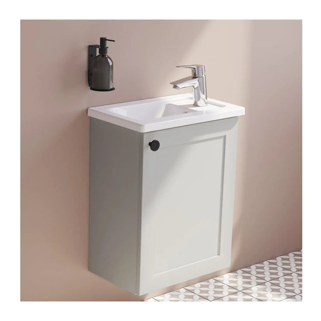 Sleek modern bathroom vanity with white ceramic sink, grey storage cabinet, chrome faucet, and wall-mounted soap dispenser on a pink wall with patterned tile floor.