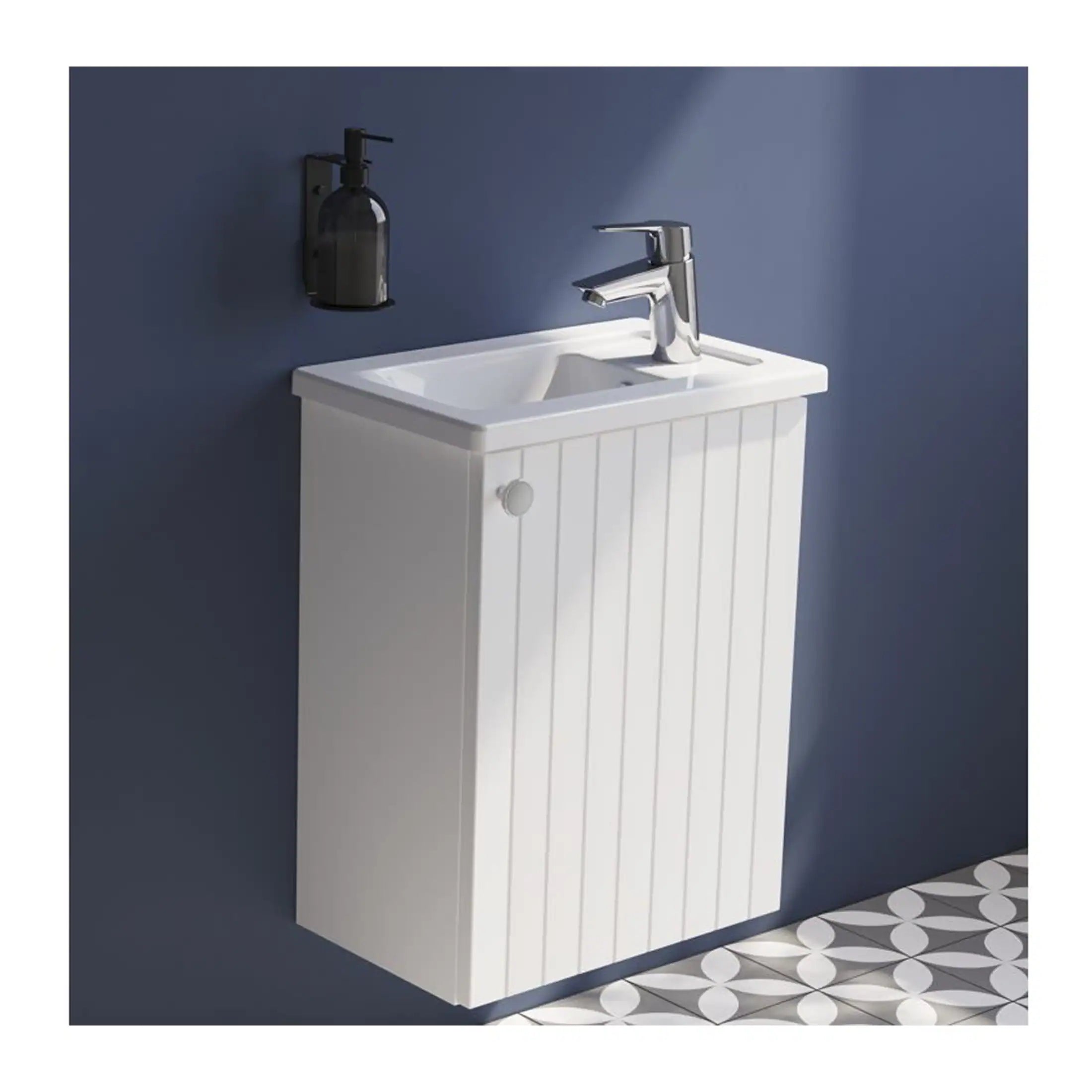 Bright white bathroom vanity with a built-in sink and chrome faucet, set against a deep blue wall, featuring a black soap dispenser and patterned floor tiles for modern bathroom decor.
