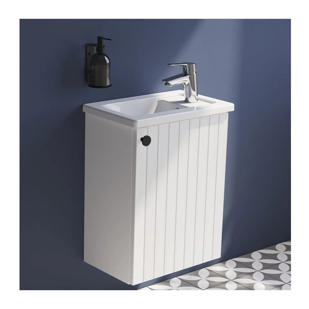 White bathroom vanity with integrated sink and modern chrome tap, set against a navy blue wall with a black soap dispenser. Perfect for compact bathroom storage and contemporary decor.