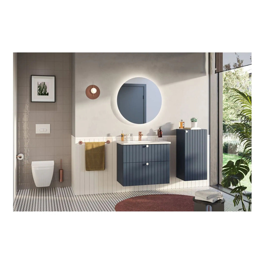Contemporary bathroom with blue cabinetry, modern round mirror with lighting, wall-mounted toilet, and decorative elements including a potted plant and patterned floor tiles, creating a stylish and functional space.