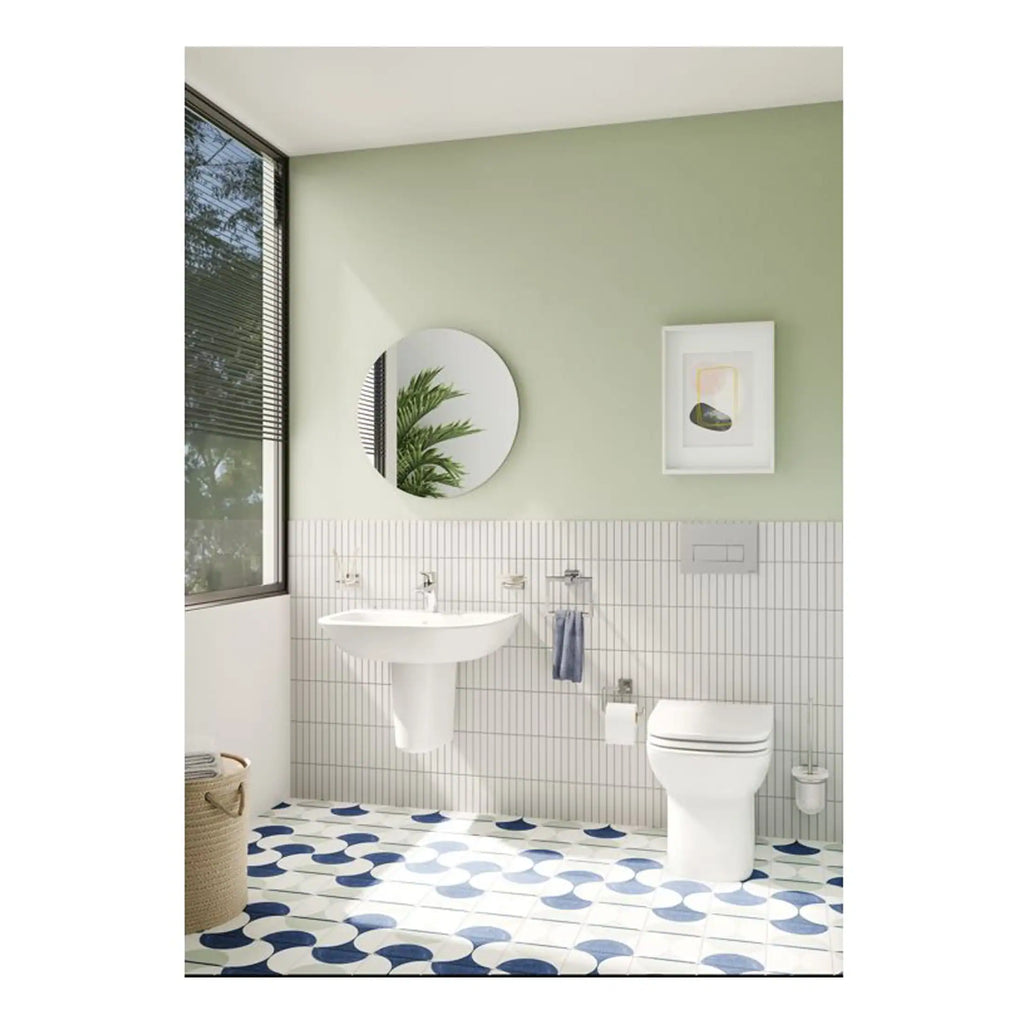 Sleek modern bathroom with wall-mounted white sink, eco-friendly toilet, circular mirror, and contemporary artwork, featuring natural light and calming colour palette for stylish bathroom design.