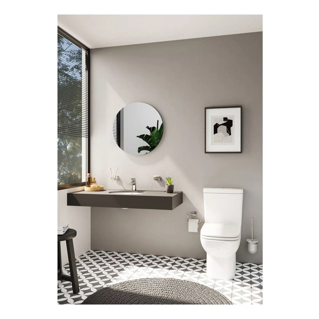 Contemporary bathroom with a sleek grey floating vanity, modern toilet, round mirror, minimalist artwork, and geometric patterned floor tiles, creating a stylish and functional space.