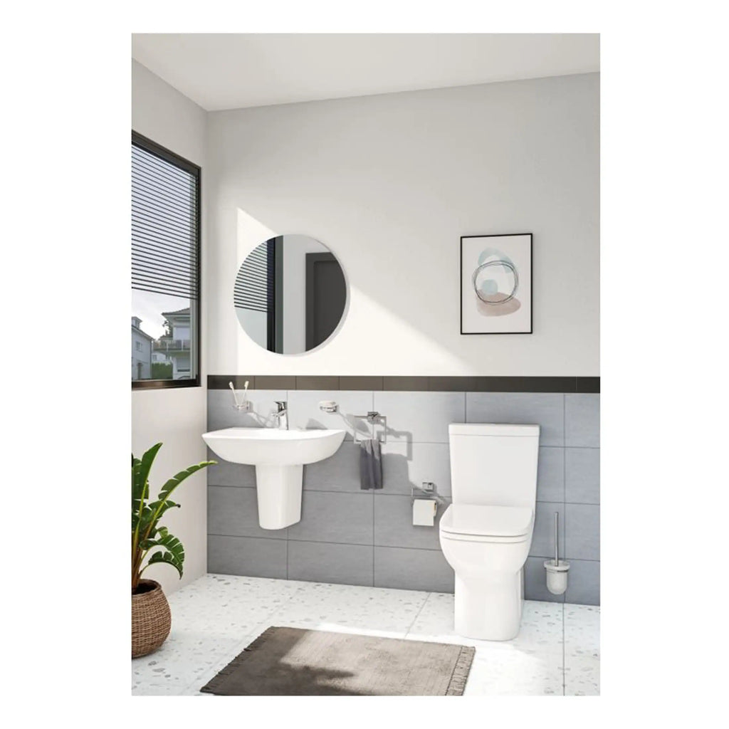 Modern bathroom with white toilet, sink, round mirror, and grey tiles, natural light, minimalist style, perfect for contemporary bathroom design.