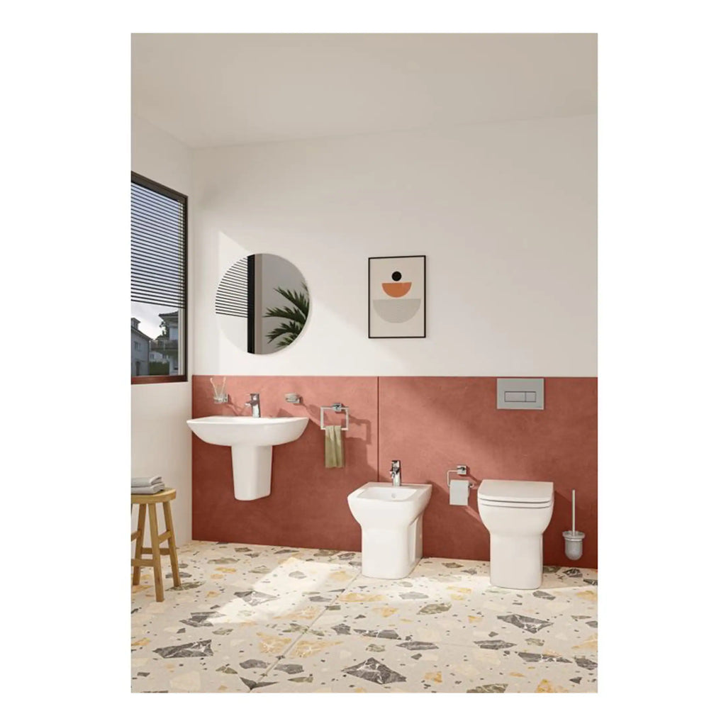 Sleek modern bathroom featuring a white wall-mounted sink, bidet, and toilet with elegant flush buttons, complemented by framed art and decorative mirror, showcasing contemporary bathroom design with stylish fixtures and terrazzo flooring.