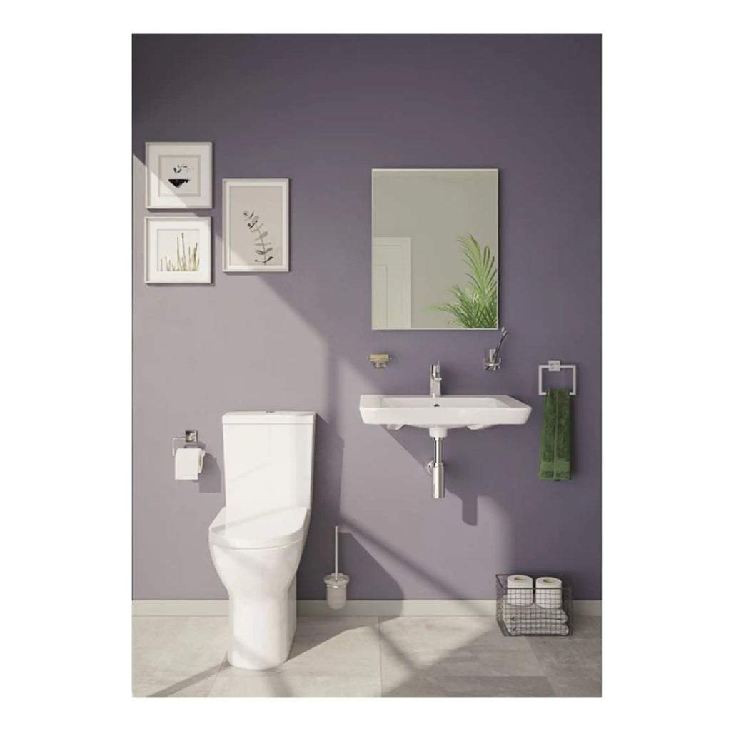 Sleek white toilet and wall-mounted sink in modern bathroom with purple accent wall, framed art, greenery, and accessories for stylish, functional bathroom decor.
