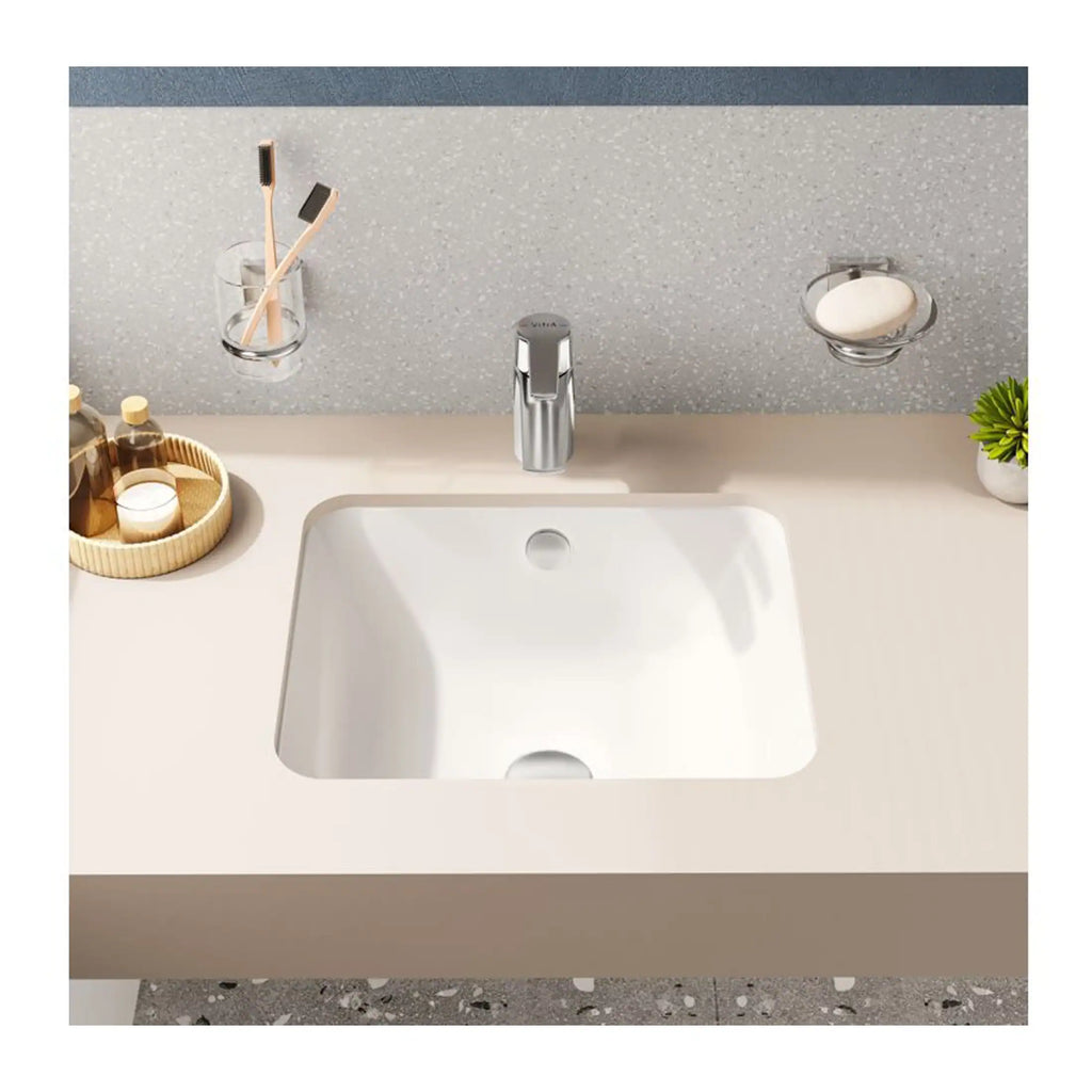 Sleek white bathroom sink with modern chrome tap, set against a textured grey backsplash with minimalistic accessories. Perfect for contemporary bathroom design and plumbing solutions.
