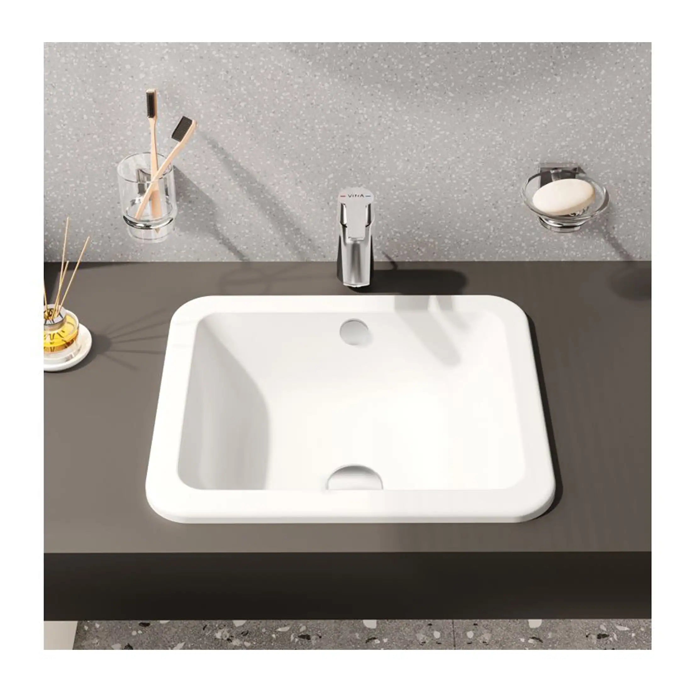 Sleek modern bathroom sink with minimalist design, featuring a chrome tap and accessories, perfect for contemporary bathroom decor.