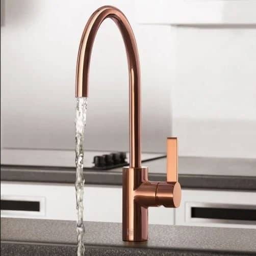 Faucet with a rose gold finish and flowing water, modern kitchen design.