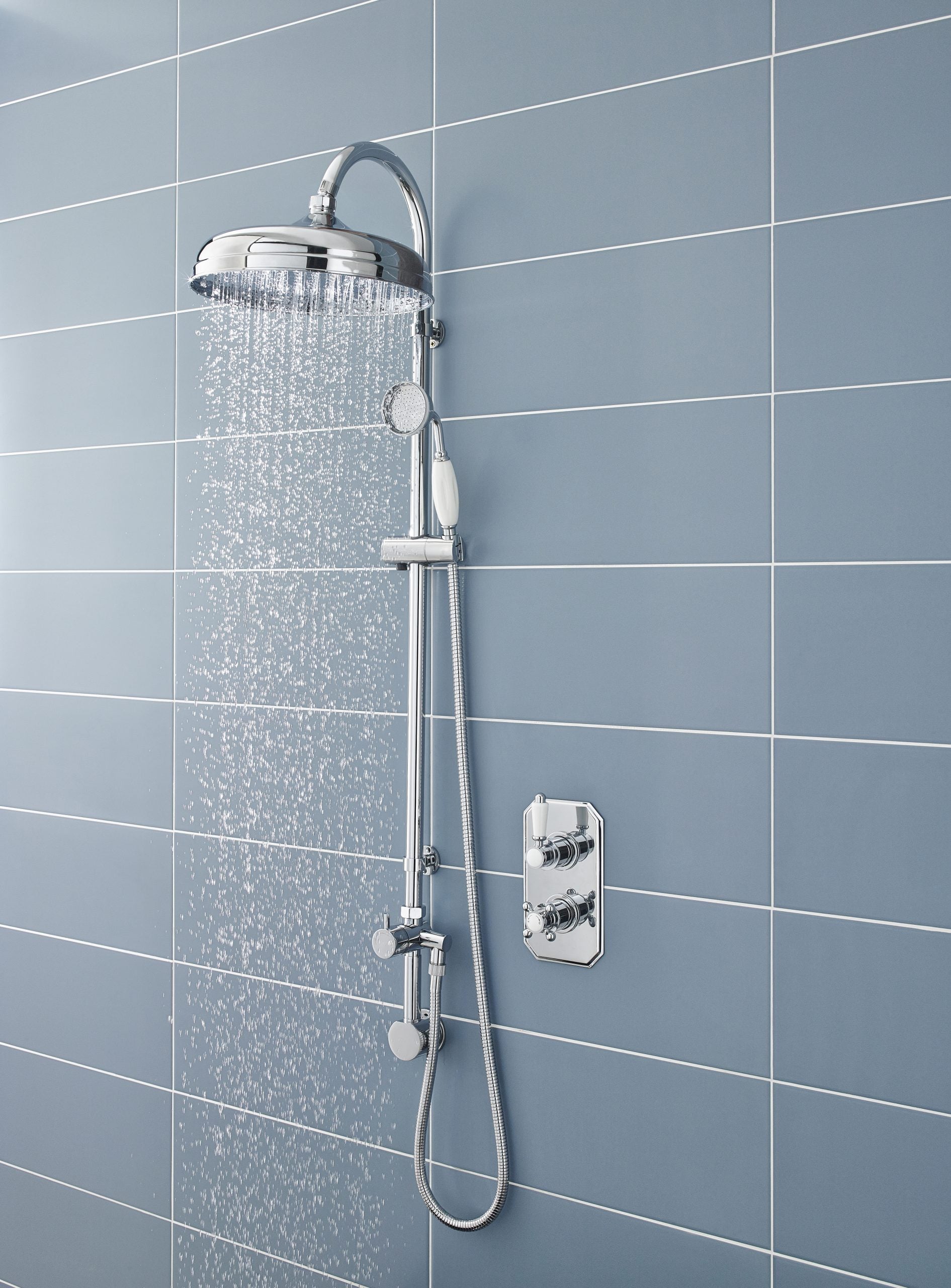 Chrome shower head with rainfall effect and handheld attachment, modern bathroom with blue wall tiles, adjustable shower controls for a luxurious shower experience.