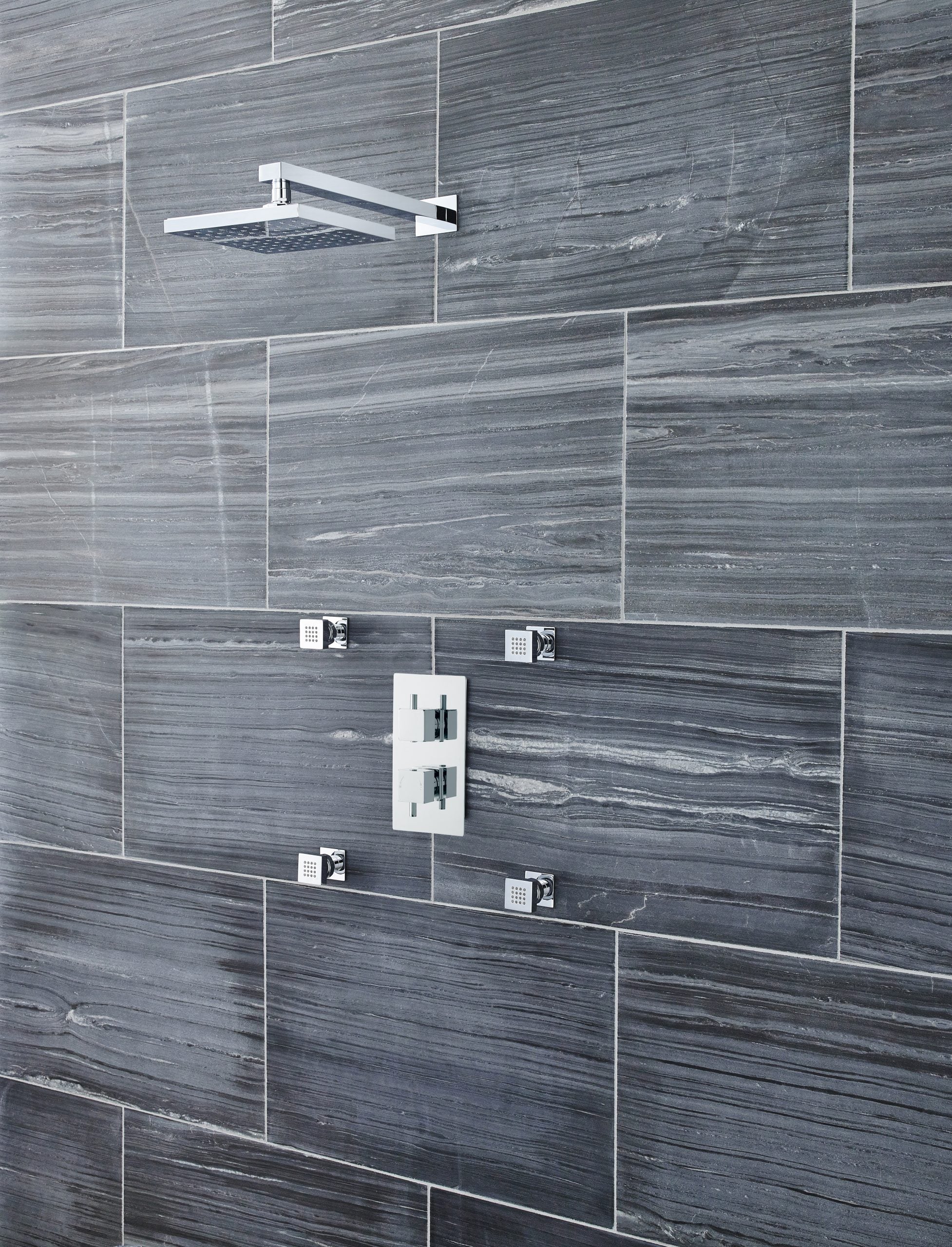Modern grey tiled shower wall with a sleek rainfall showerhead and contemporary mixer controls, ideal for luxury bathroom renovations and stylish wet room designs.