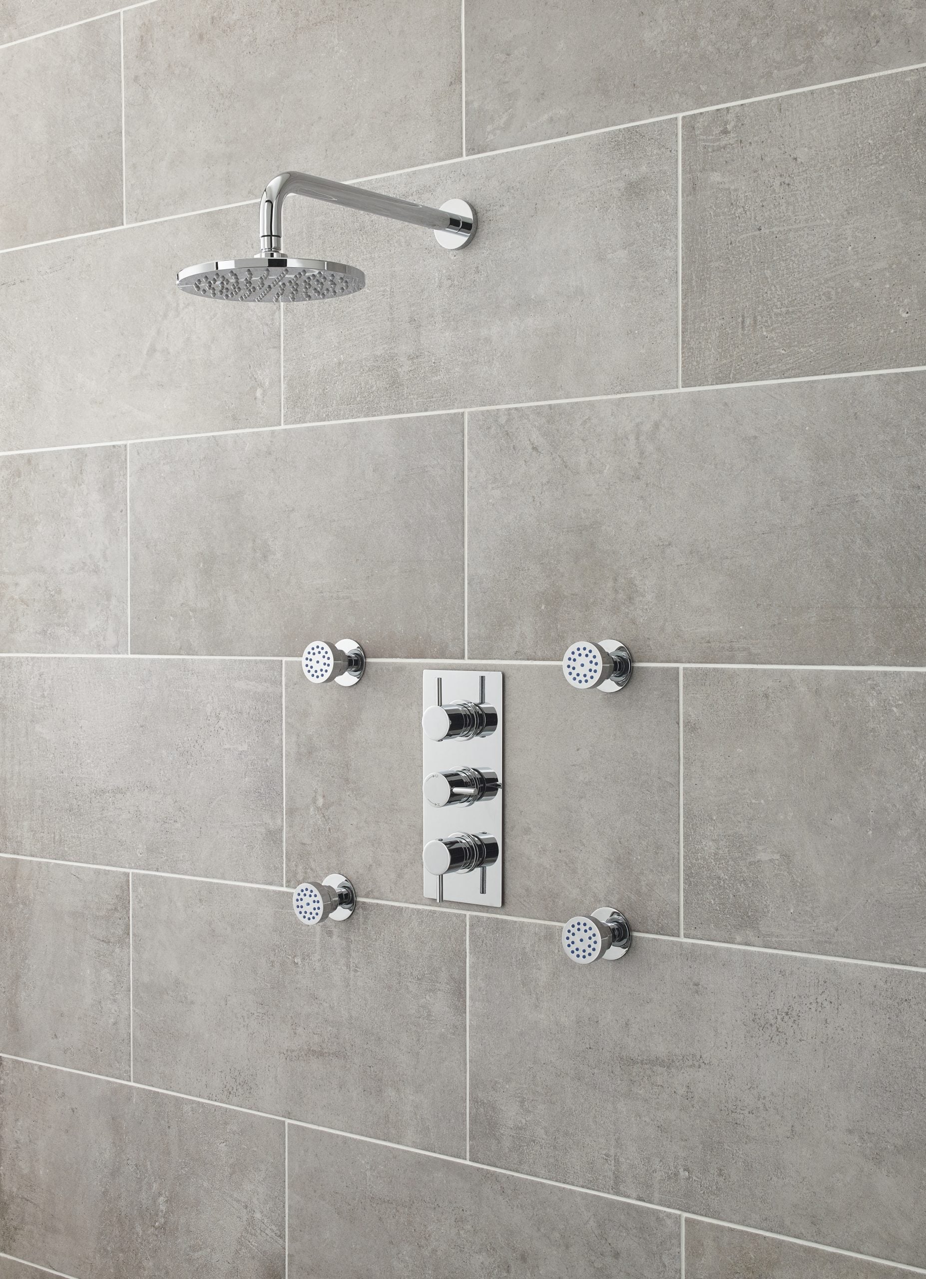 Sleek chrome shower panel with overhead rain shower and multiple body jets on a modern tiled bathroom wall, perfect for luxurious and contemporary bathroom design.