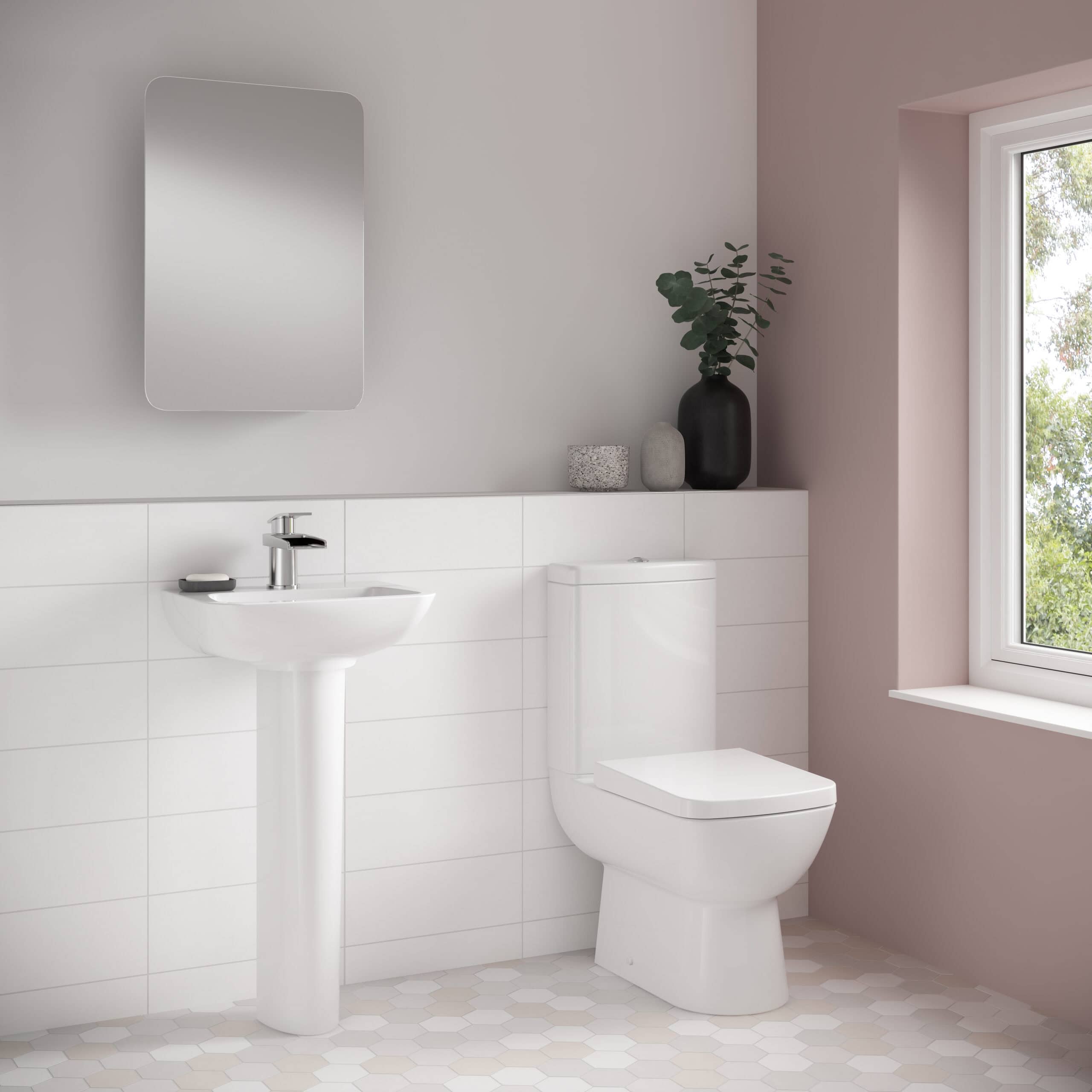 Minimalist bathroom with white sanitary ware, pedestal sink, modern toilet, and decorative vases in soft pink and neutral tones with a large window and natural light.