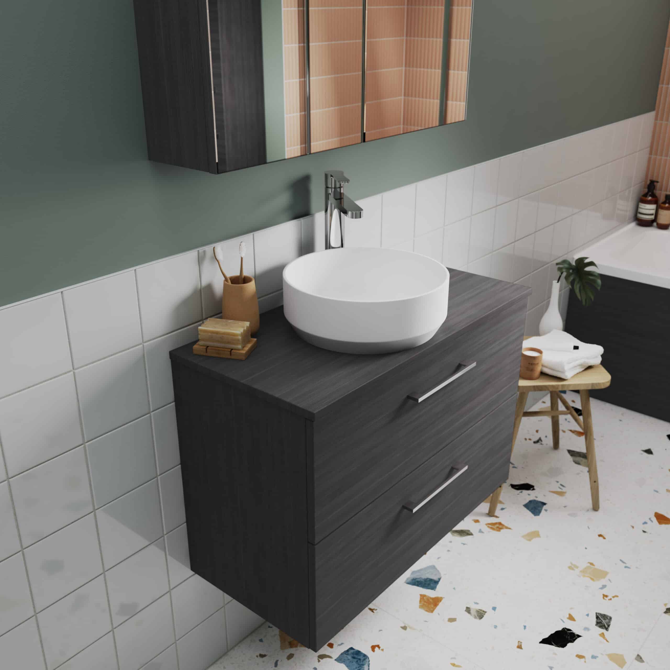 Modern bathroom vanity unit with a round vessel sink and sleek chrome tap, featuring dark wood finish, set against a green wall with tiled accents and stylish decor.
