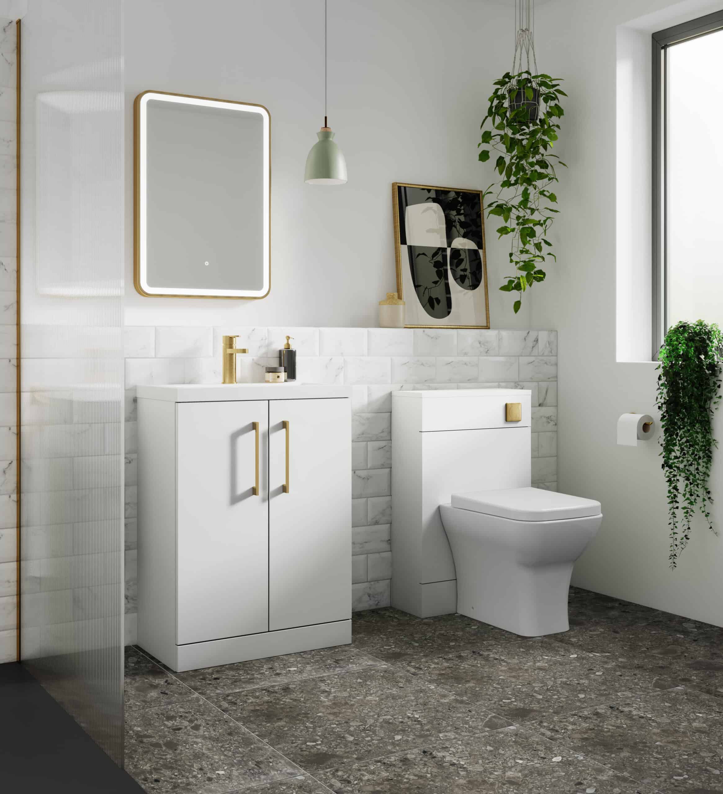 Sleek modern white bathroom vanity with gold handles, gold faucet, and matching toilet, complemented by marble tiles and lush green plants, creating a stylish and contemporary bubble bath space.