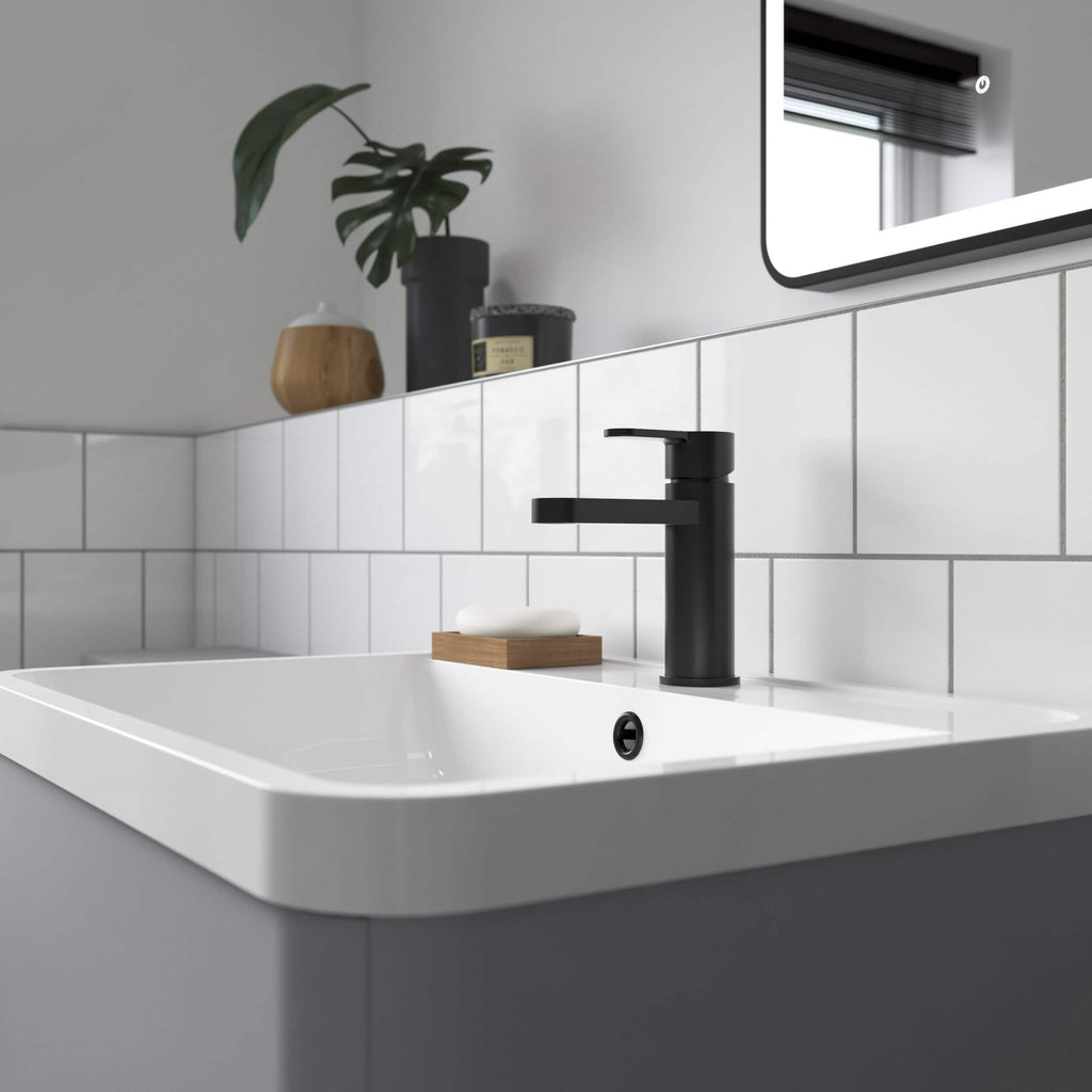 Sleek black bathroom sink faucet on white tiled wall with minimalist decor, modern bathroom design, and black accents.
