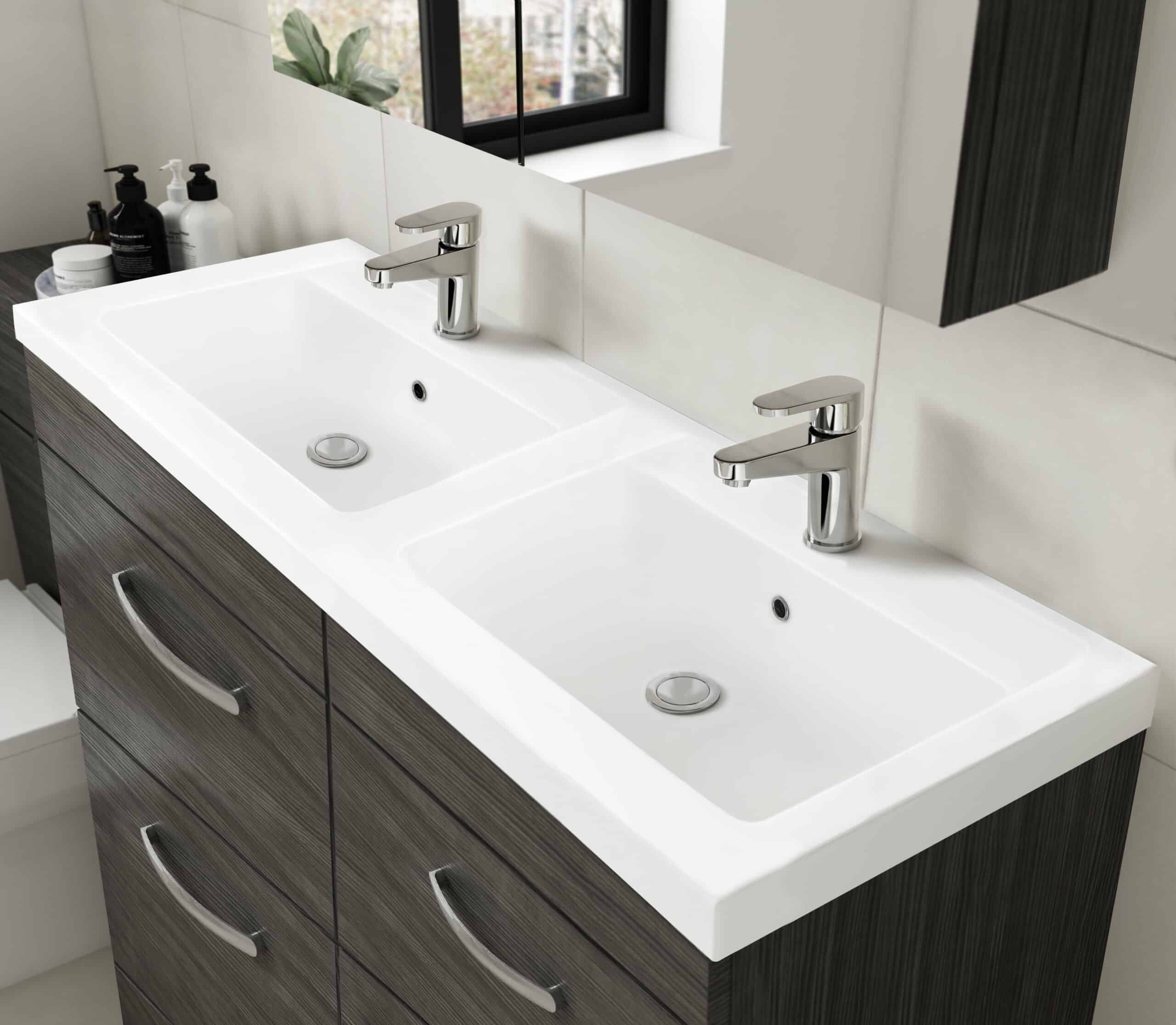 Double ceramic bathroom sink with modern chrome mixers on a dark wood vanity unit. Ideal for contemporary bathrooms, featuring a minimalist design with ample storage and sleek fixtures.
