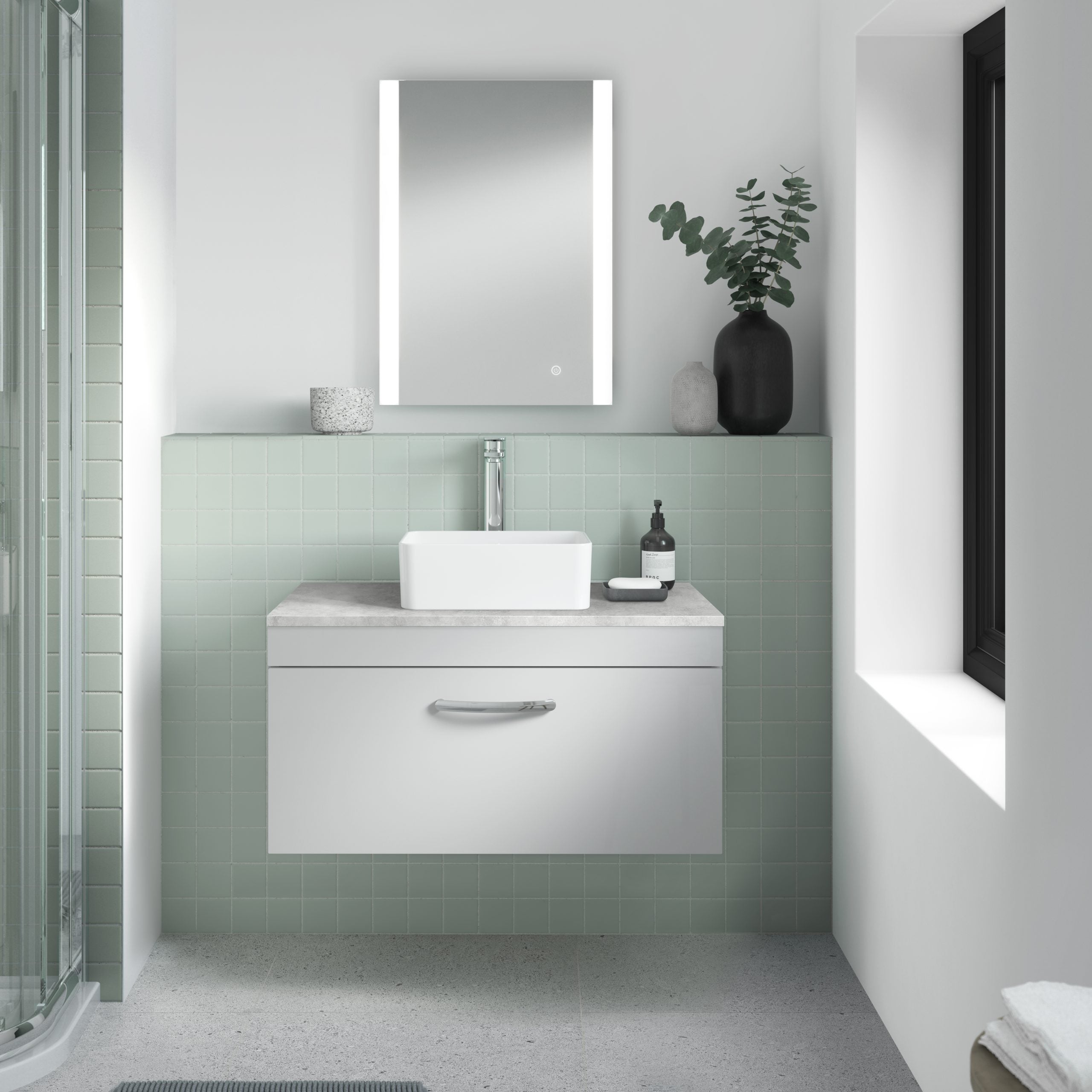 Modern minimalist bathroom with standalone sink and contemporary decor, featuring soft green tile accents and sleek black and grey decorative accessories, perfect for bathroom renovation ideas.