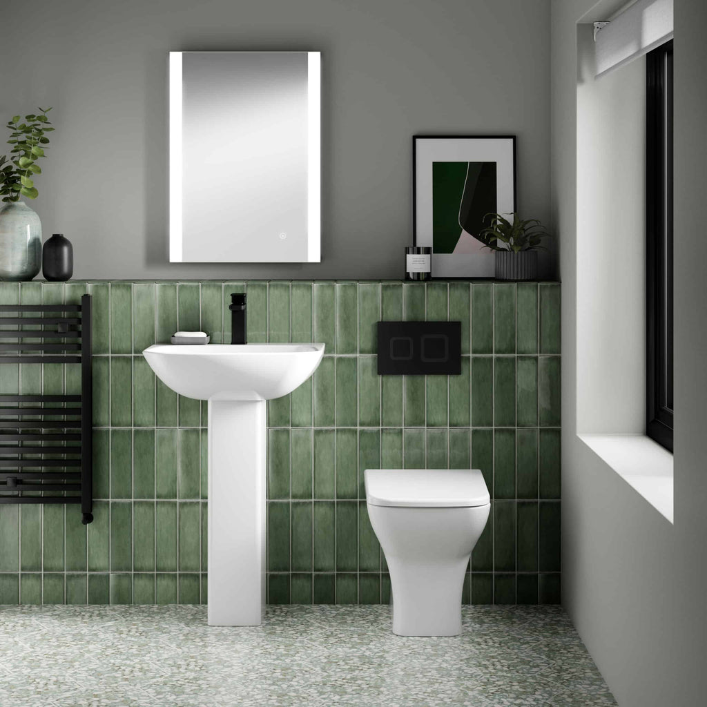 Contemporary bathroom featuring a sleek white pedestal sink, modern toilet, green tiled walls, and minimalist decor, highlighting stylish and functional bathroom design for Birmingham homes.