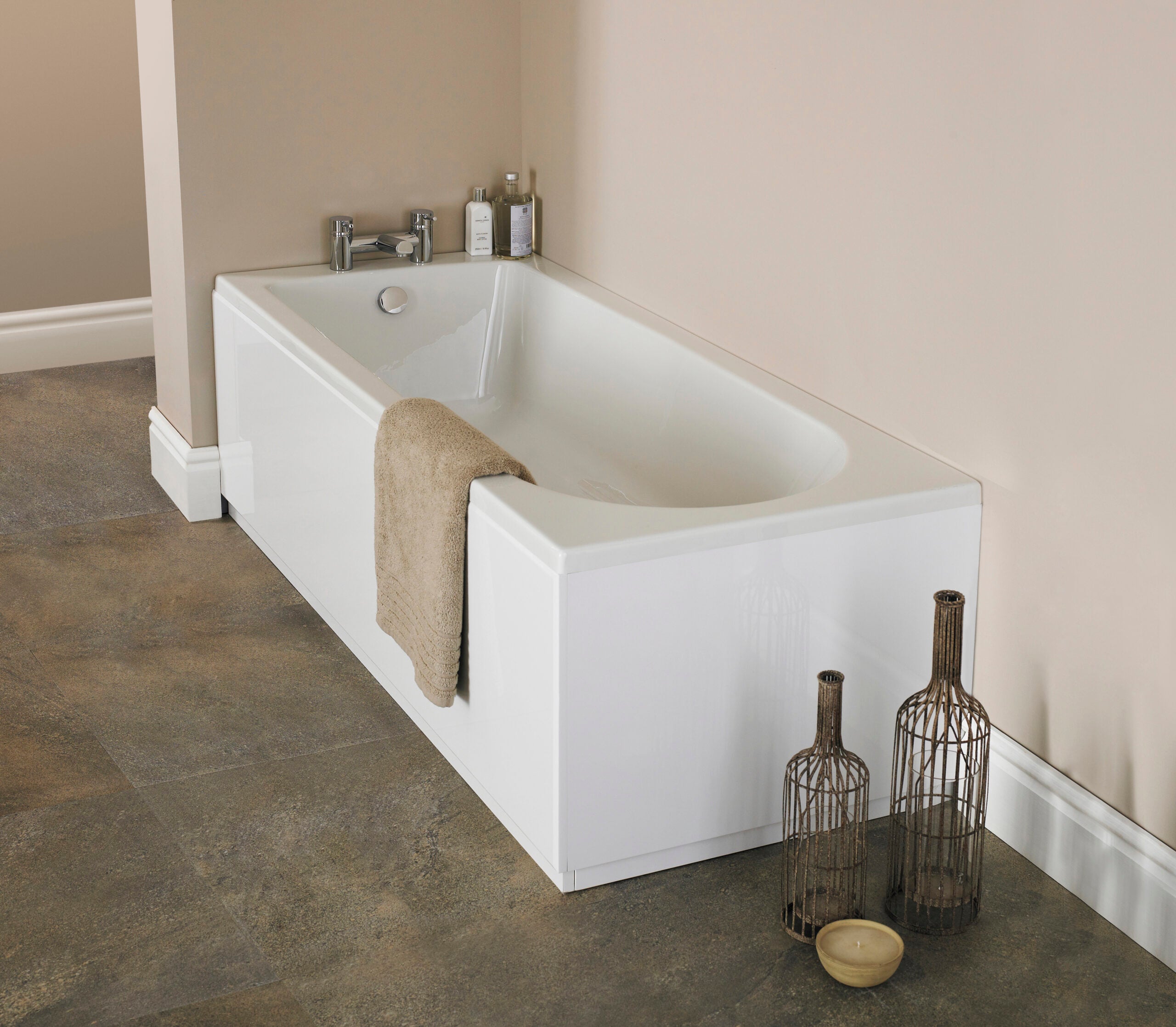 Modern white bathtub with beige towel and decorative vases in a contemporary bathroom setting.