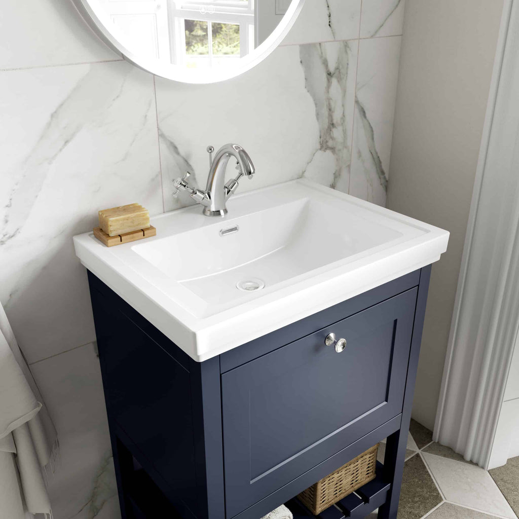 Polished bathroom vanity with white sink and chrome faucet in a modern ensuite, featuring marble wall tiles and a round mirror. Elegant and functional bathroom design by Bubly Bathrooms.