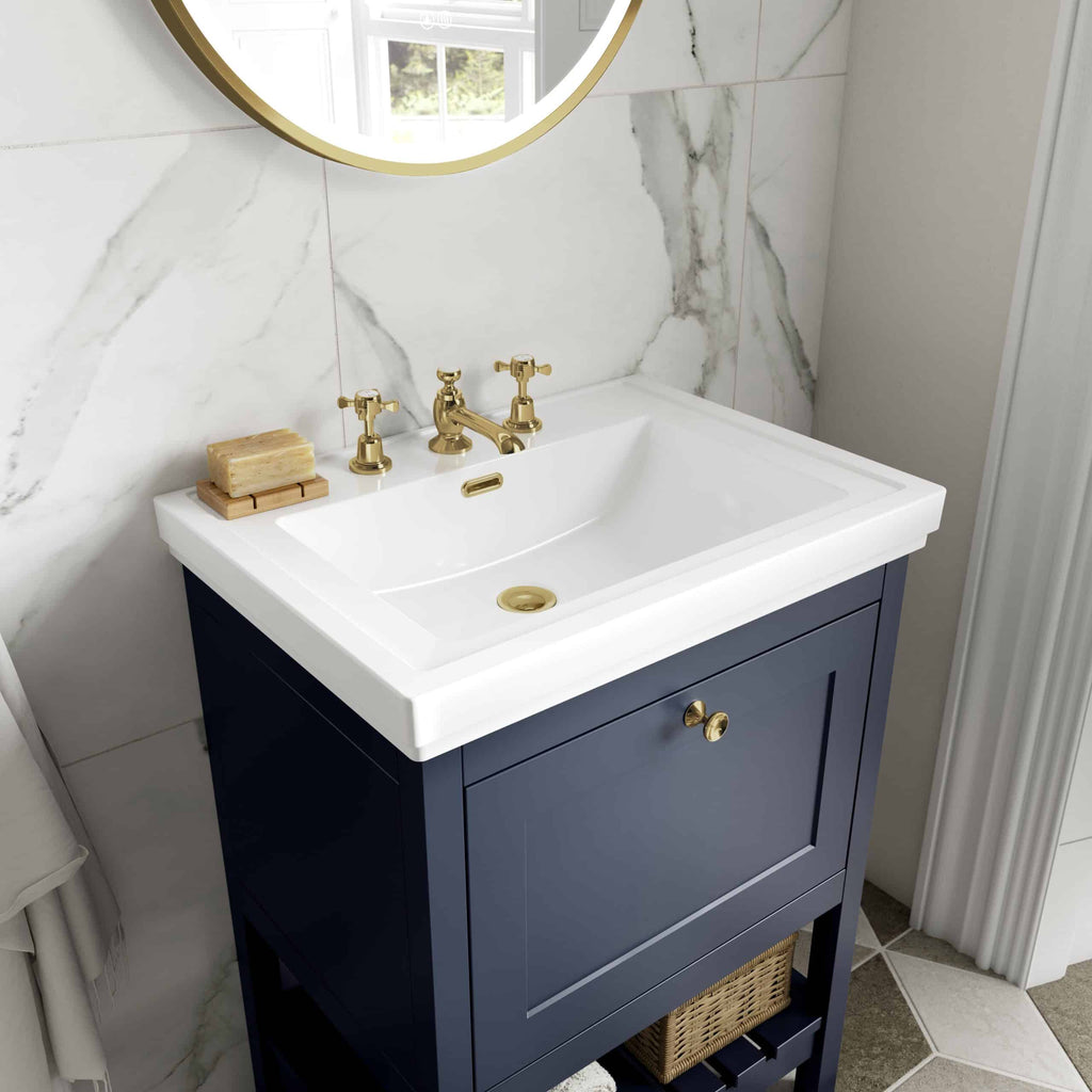 Classic bathroom vanity with navy blue cabinet and white ceramic sink, featuring gold fixtures and a marble backsplash for luxurious bathroom design.