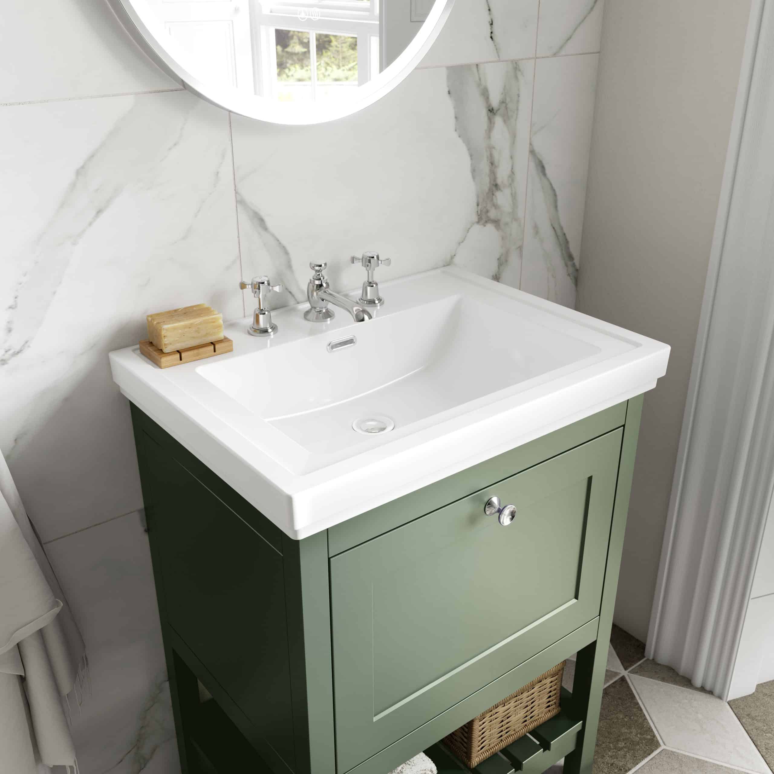 Vintage green bathroom vanity with a white ceramic sink and chrome taps, set against marble wall tiles; elegant and functional bathroom decor.